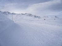 snow covered slope in the middle of a ski area as people ski on it near ski lift