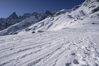 a person riding skis down a snow covered slope past a mountain peak while holding onto his ski poles