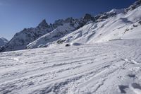 a person riding skis down a snow covered slope past a mountain peak while holding onto his ski poles