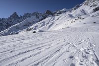 a person riding skis down a snow covered slope past a mountain peak while holding onto his ski poles