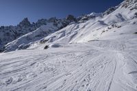 a person riding skis down a snow covered slope past a mountain peak while holding onto his ski poles