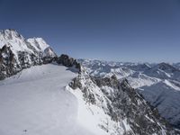 a man skiing up a snowy mountain slope in the sun and the mountains are covered with snow