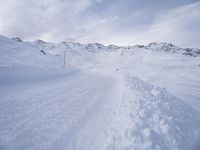 snow covered slope in the middle of a ski area as people ski on it near ski lift