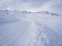snow covered slope in the middle of a ski area as people ski on it near ski lift