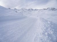 snow covered slope in the middle of a ski area as people ski on it near ski lift