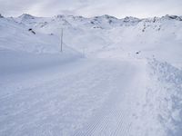 snow covered slope in the middle of a ski area as people ski on it near ski lift