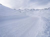 snow covered slope in the middle of a ski area as people ski on it near ski lift