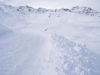 snow covered slope in the middle of a ski area as people ski on it near ski lift