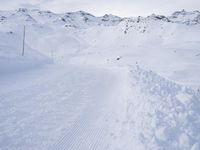 snow covered slope in the middle of a ski area as people ski on it near ski lift