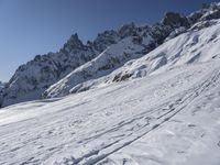 a skier on a mountain in the sun with snow covering the terrain below him and above him