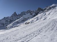 a skier on a mountain in the sun with snow covering the terrain below him and above him