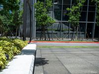 a red fire hydrant sitting outside of a large glass building next to grass and trees