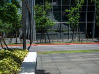 a red fire hydrant sitting outside of a large glass building next to grass and trees