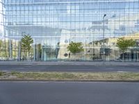 a glass building that is next to a street and trees on it's corner