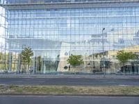 a glass building that is next to a street and trees on it's corner