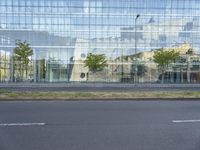 a glass building that is next to a street and trees on it's corner