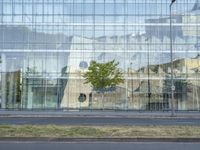 a glass building that is next to a street and trees on it's corner