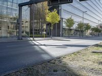 a glass building reflecting in another office building, a street is empty except for cars to pass