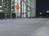 a city sidewalk with two people walking in the distance and a glass building and stairs