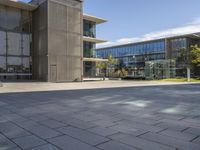 a building with glass walls and a sidewalk in front of it in sunny weather outside