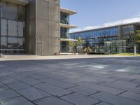 a building with glass walls and a sidewalk in front of it in sunny weather outside