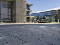 a building with glass walls and a sidewalk in front of it in sunny weather outside