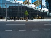 a view of a glass building on a city street with trees in the foreground