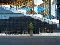 a view of a glass building on a city street with trees in the foreground