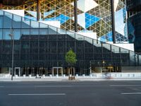 a view of a glass building on a city street with trees in the foreground