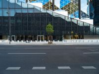 a view of a glass building on a city street with trees in the foreground