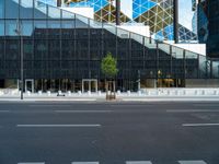 a view of a glass building on a city street with trees in the foreground