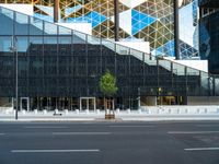 a view of a glass building on a city street with trees in the foreground