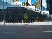 a view of a glass building on a city street with trees in the foreground