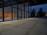 outside patio in evening with trees and lights near doors and benches, glass wall to side