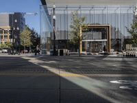 a glassy building next to a street with bicycles and cars parked near it and a man on the sidewalk