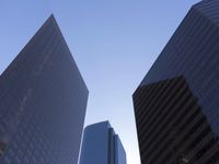 a tall glass building stands tall in front of a blue sky and some buildings with several windows