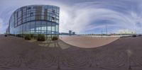 a fisheye lens of a glass building with cars on the street in front of it