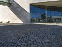 a brick road sits next to a glass building as the sun shines in front