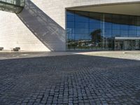 a brick road sits next to a glass building as the sun shines in front