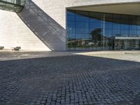 a brick road sits next to a glass building as the sun shines in front