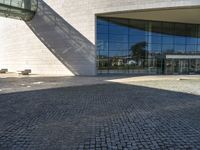 a brick road sits next to a glass building as the sun shines in front