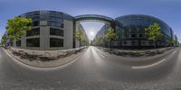 a building that is made of glass on the street with trees growing up from it