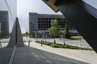 a person walking down a walkway near a glass building, next to a sidewalk and walkway