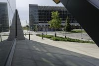 a person walking down a walkway near a glass building, next to a sidewalk and walkway