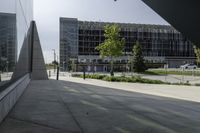 a person walking down a walkway near a glass building, next to a sidewalk and walkway