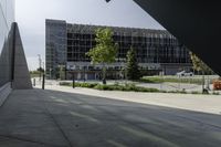 a person walking down a walkway near a glass building, next to a sidewalk and walkway