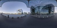 a view of a large glass covered building through a circular mirror showing the building and its architecture