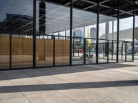 glass walls with a woman walking down the sidewalk in front of it in a public place