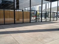 glass walls with a woman walking down the sidewalk in front of it in a public place