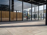 glass walls with a woman walking down the sidewalk in front of it in a public place